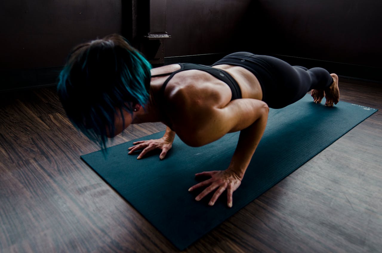 Atleta femenina realizando una intensa rutina de ejercicios para hombros con una plancha dinámica sobre una esterilla de yoga