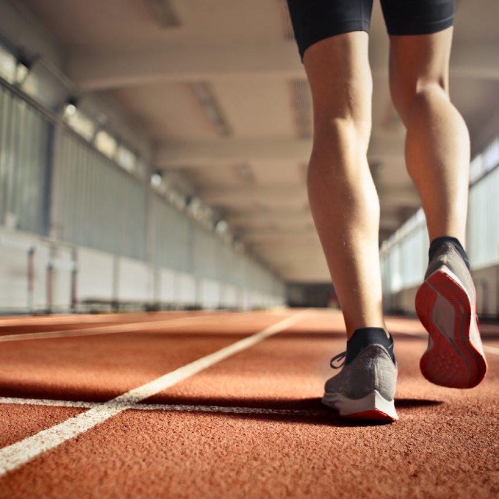 Atleta corriendo en una pista, trabajando en su rutina de ejercicios para piernas