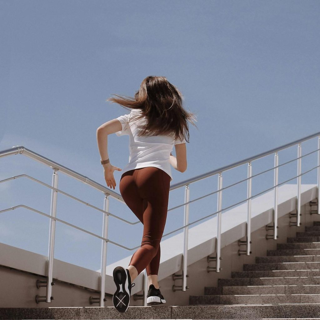 Una mujer subiendo escaleras al aire libre como parte de sus rutinas de piernas y glúteos.